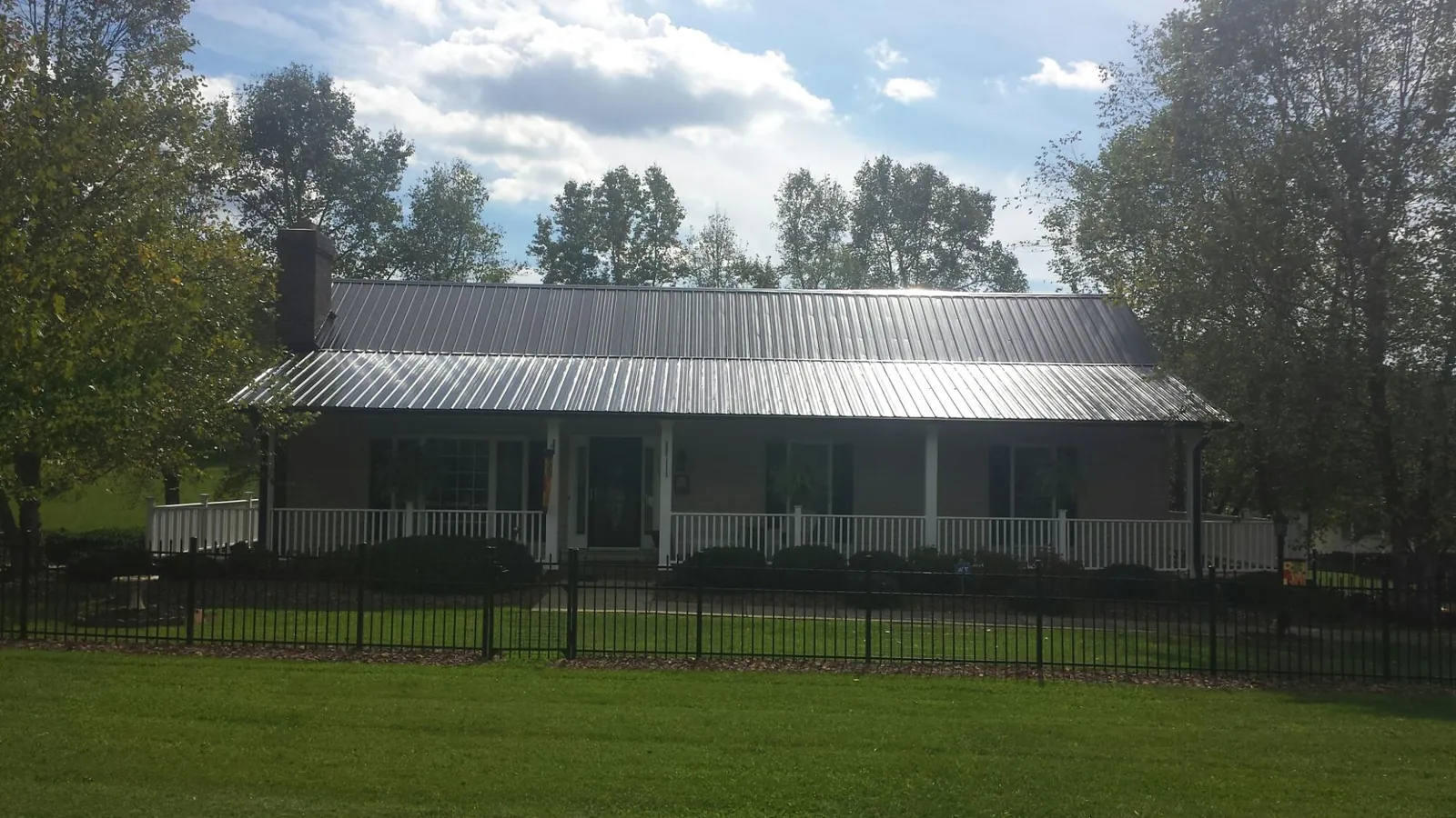 Gray metal roof on a brick ranch with a full width front porch — Gutter Guard Installation work by our crew in Walcott